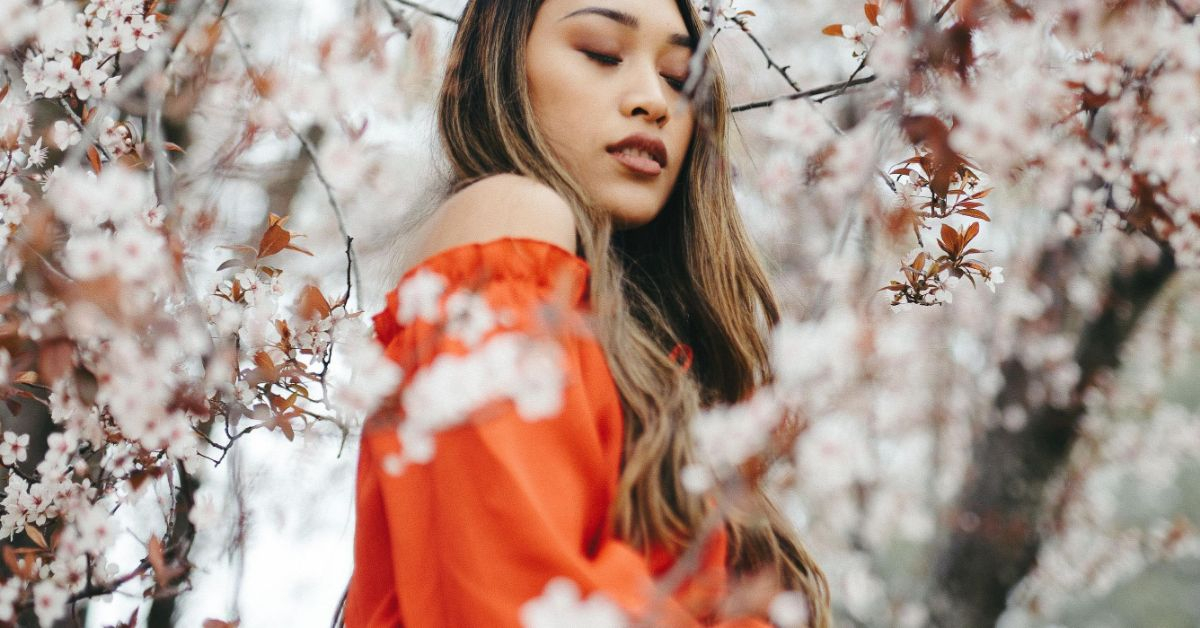 Ethical Brand Directory Blog | Stylists Picks: Spring Wardrobe Essentials | Model wearing red dress posing next to cherry blossom tree