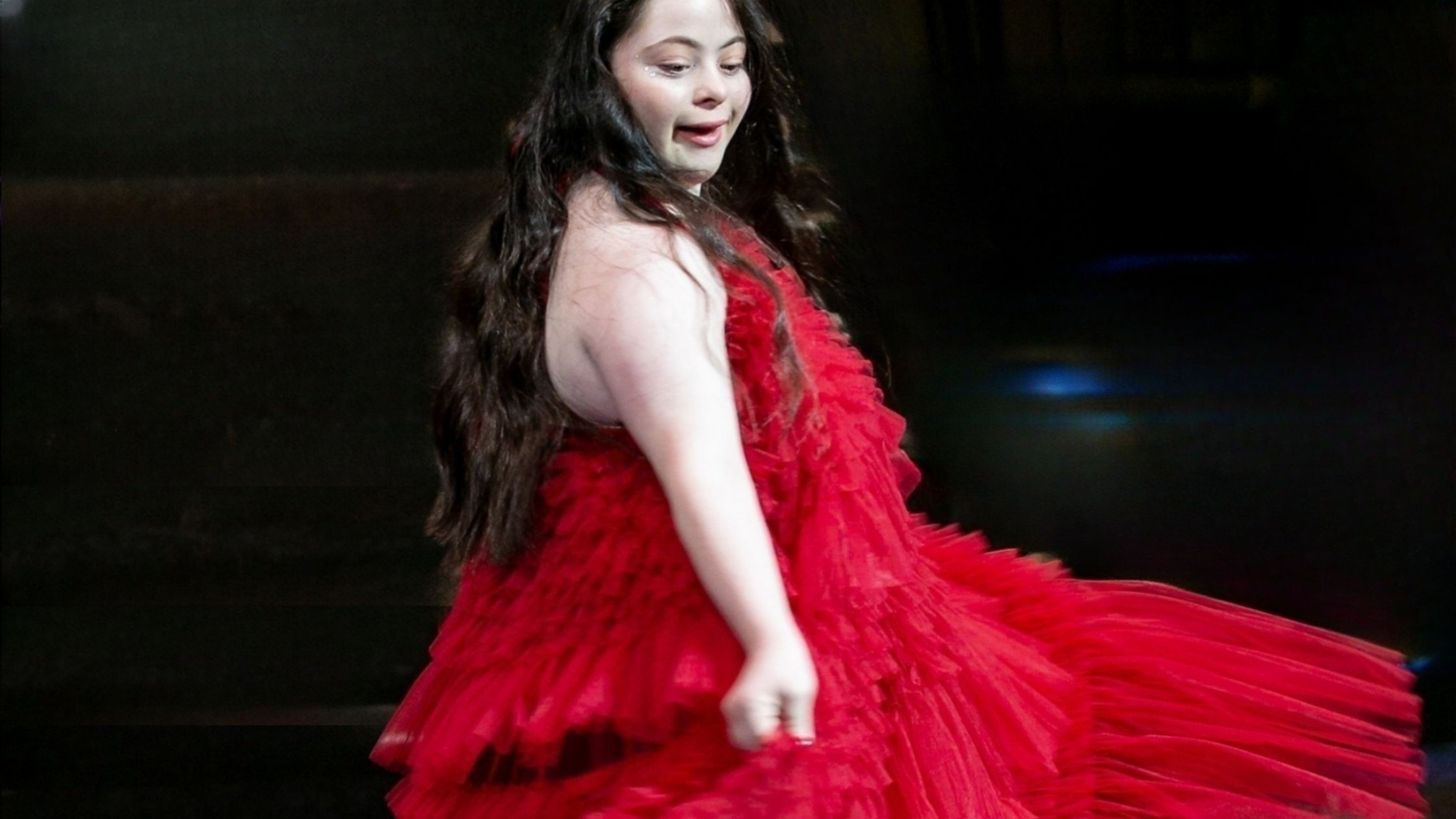 Ellie Goldstein on the catwalk in a red dress